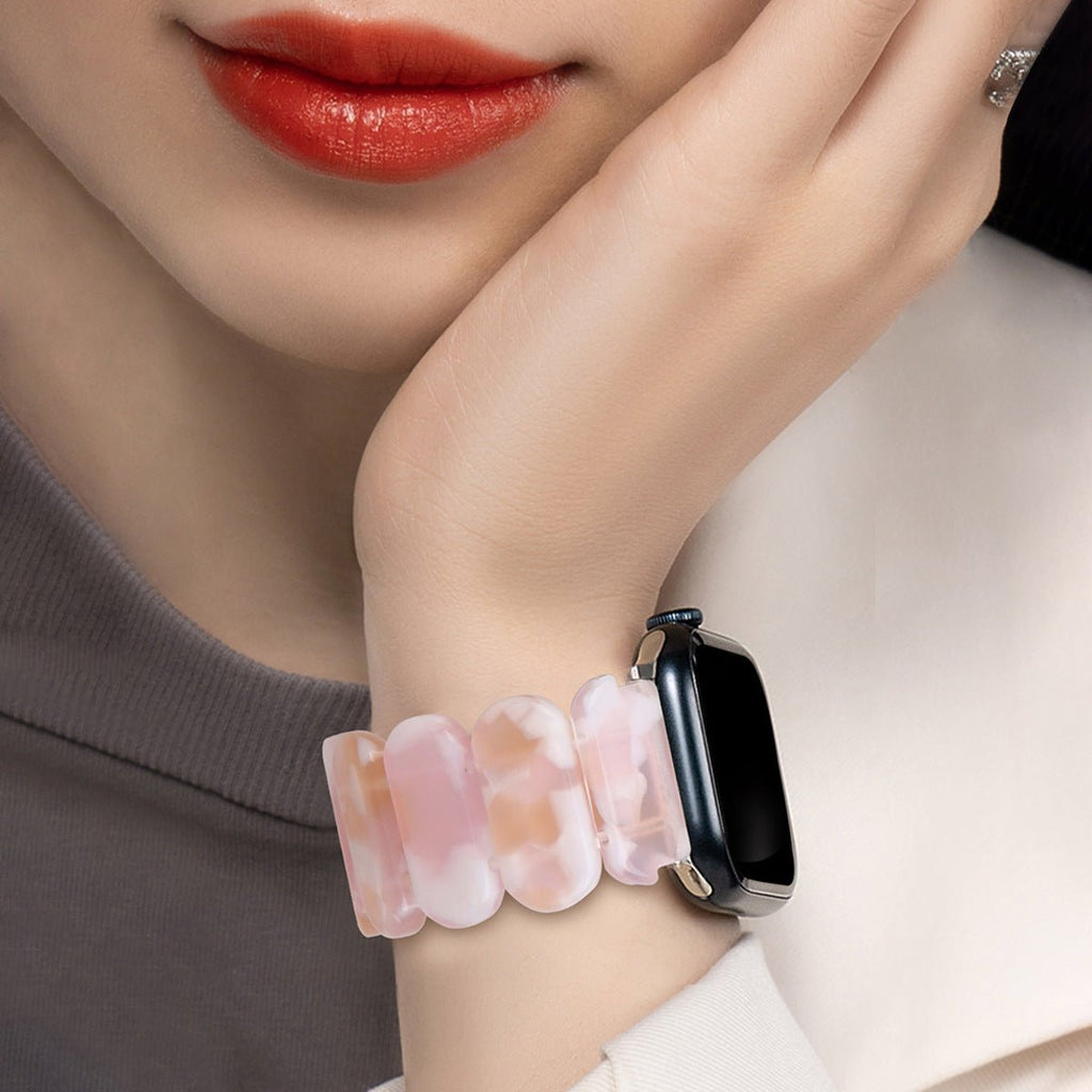 Bracelet en résine rose pâle à motifs nuageux pour Apple Watch porté au poignet féminin.