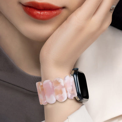 Bracelet en résine rose pâle à motifs nuageux pour Apple Watch porté au poignet féminin.