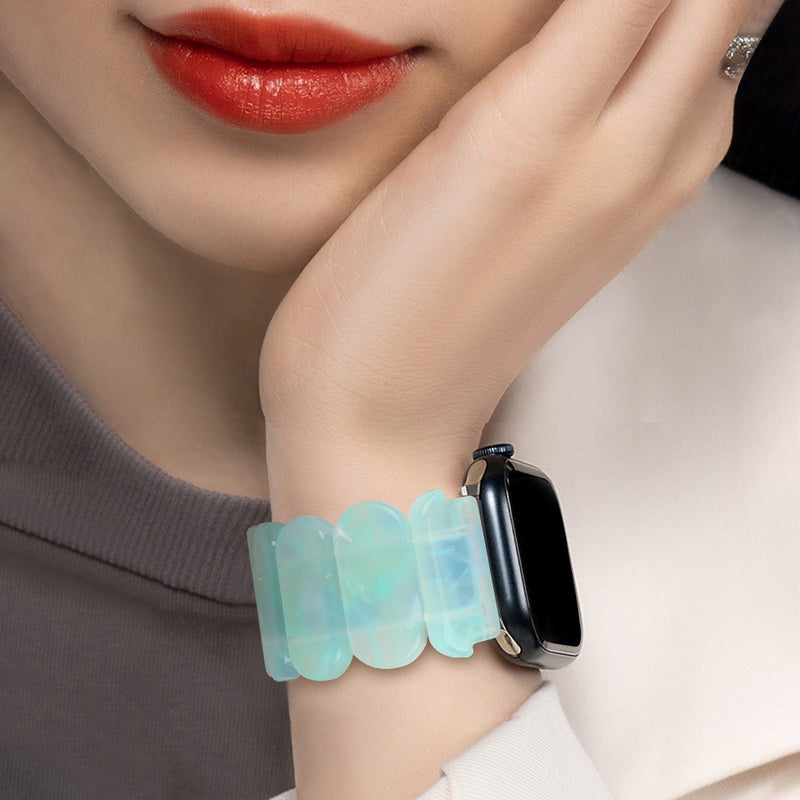 Bracelet Apple Watch femme en résine bleu clair translucide avec maillons larges et fermoir noir.