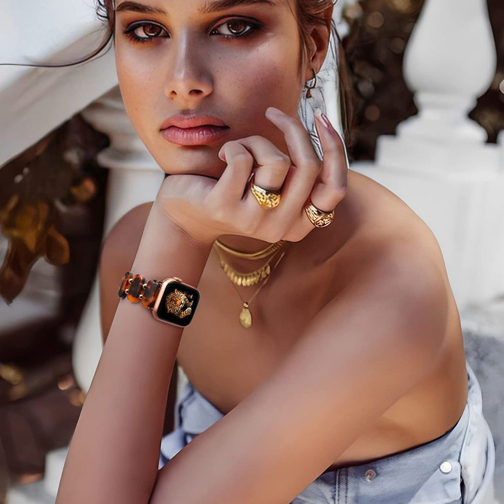 Bracelet Apple Watch en résine motif léopard marron sur poignet féminin élégant.