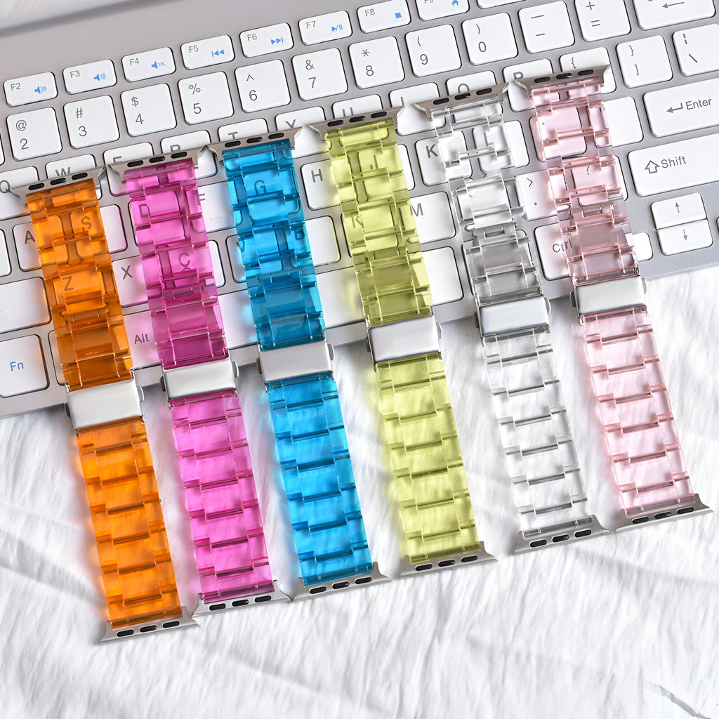 Six bracelets Apple Watch en résine transparente aux couleurs orange, rose, bleu, jaune, clair et rose pâle, affichés sur un .