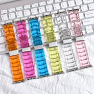 Six bracelets Apple Watch en résine transparente aux couleurs orange, rose, bleu, jaune, clair et rose pâle, affichés sur un .