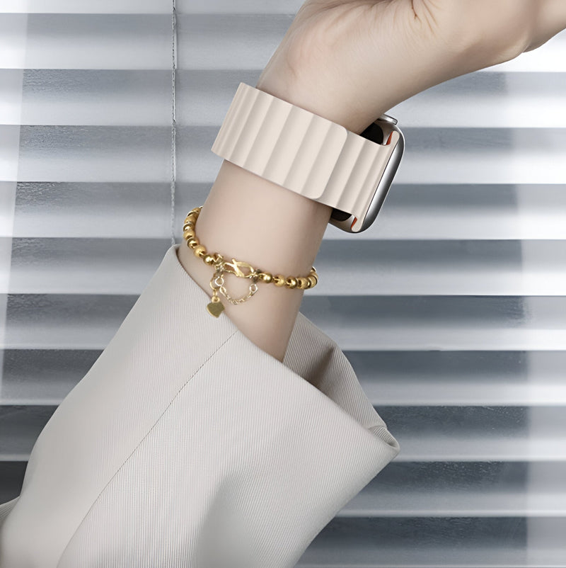 Bracelet Apple Watch en silicone beige clair à texture nervurée, porté avec un bracelet doré élégant.