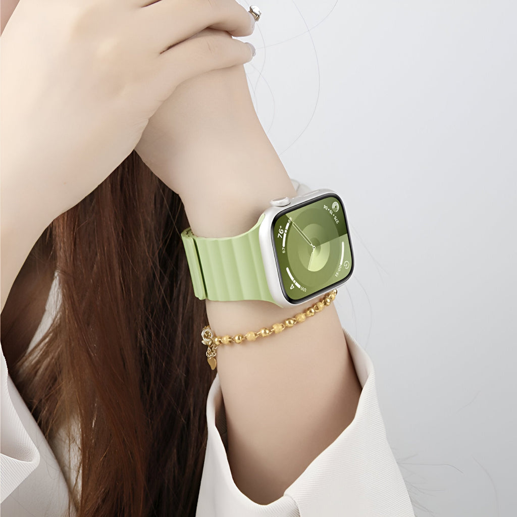 Bracelet Apple Watch en silicone vert menthe, style sport, porté au poignet avec montre carrée argentée.