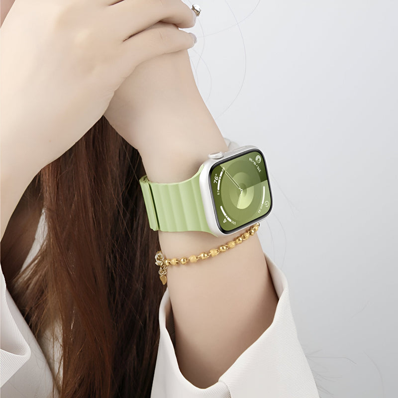 Bracelet Apple Watch en silicone vert menthe, style sport, porté au poignet avec montre carrée argentée.