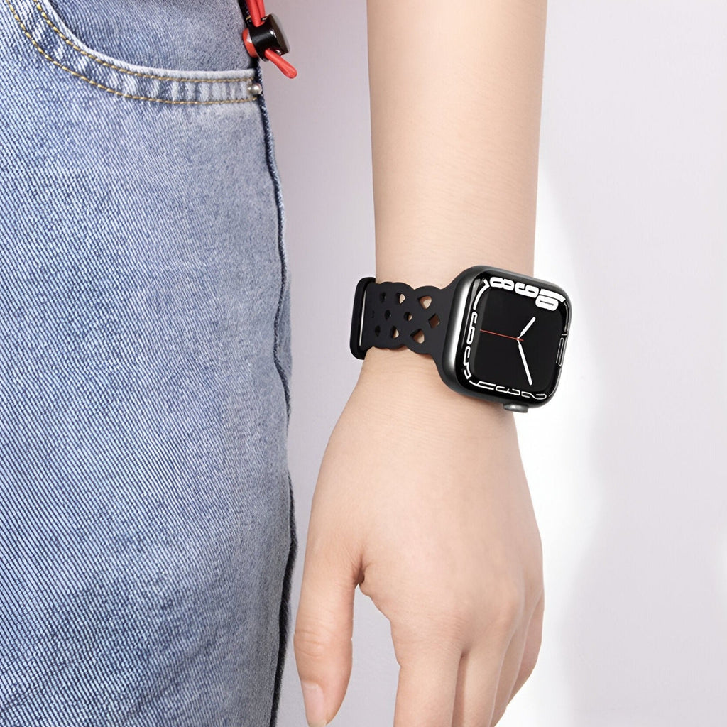 Bracelet Apple Watch silicone noir avec perforations, modèle Astra, porté au poignet féminin.