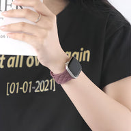 Bracelet Apple Watch en silicone pourpre tressé, ajustable, modèle Caliope, porté au poignet.