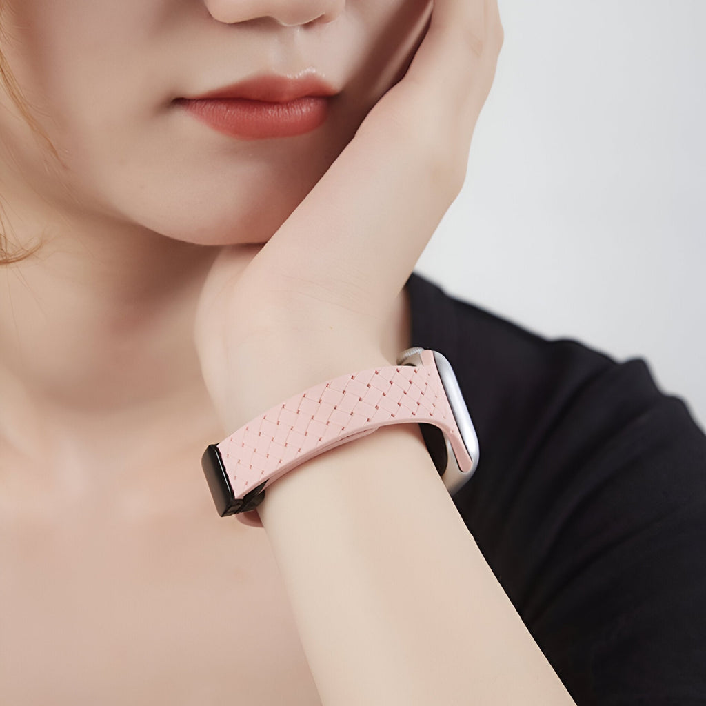 Bracelet Apple Watch en silicone rose clair avec texture perforée, modèle Feryn, porté au poignet.