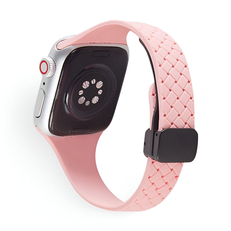Bracelet Apple Watch en silicone rose clair, texture tressée, boucle noire ajustable.