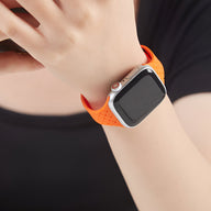 Bracelet Apple Watch en silicone orange perforé, style sportif, ajusté au poignet.