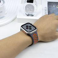 Bracelet Apple Watch Nyro en silicone noir avec perforations orange sur poignet féminin.
