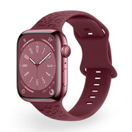 Bracelet en silicone bordeaux pour Apple Watch avec motifs gravés, finition lisse et boucle ajustable.