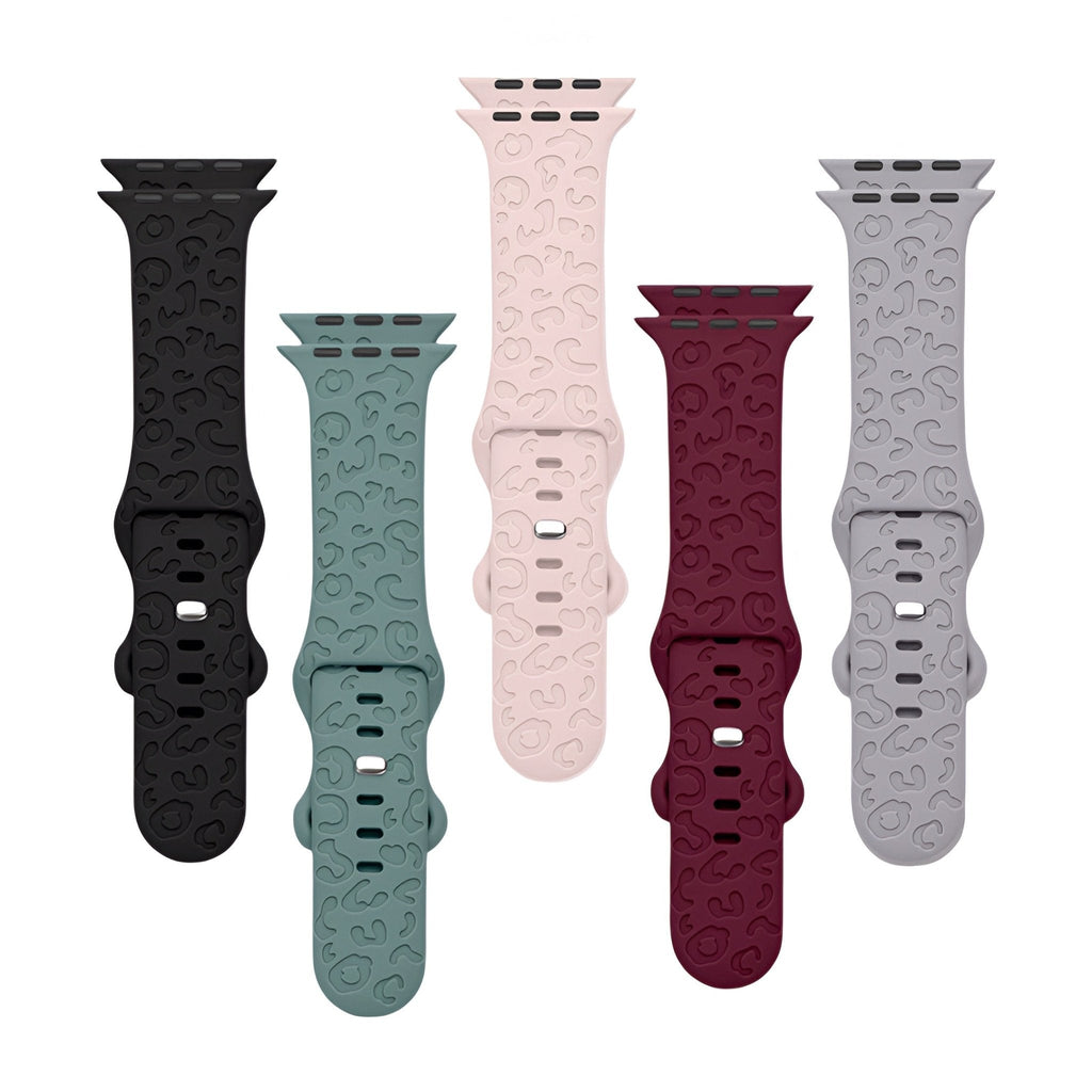 Cinq bracelets Apple Watch en silicone aux couleurs noir, vert clair, rose, rouge bordeaux et gris, textures élégantes,.