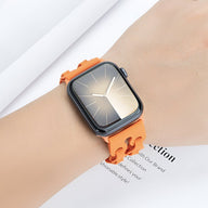 Bracelet Apple Watch en silicone orange avec maillons incurvés sur poignet clair.