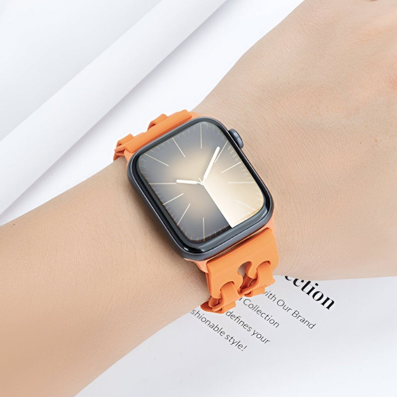 Bracelet Apple Watch en silicone orange avec maillons incurvés sur poignet clair.