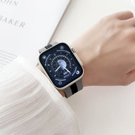 Bracelet Apple Watch en silicone noir et gris, design bicolore ajusté au poignet féminin.
