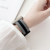 Bracelet Apple Watch en silicone gris et noir avec boucle en métal, porté sur poignet féminin.