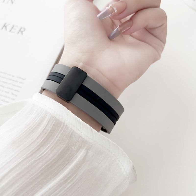 Bracelet Apple Watch en silicone noir et gris, pour femme, modèle Faelan, porté au poignet.