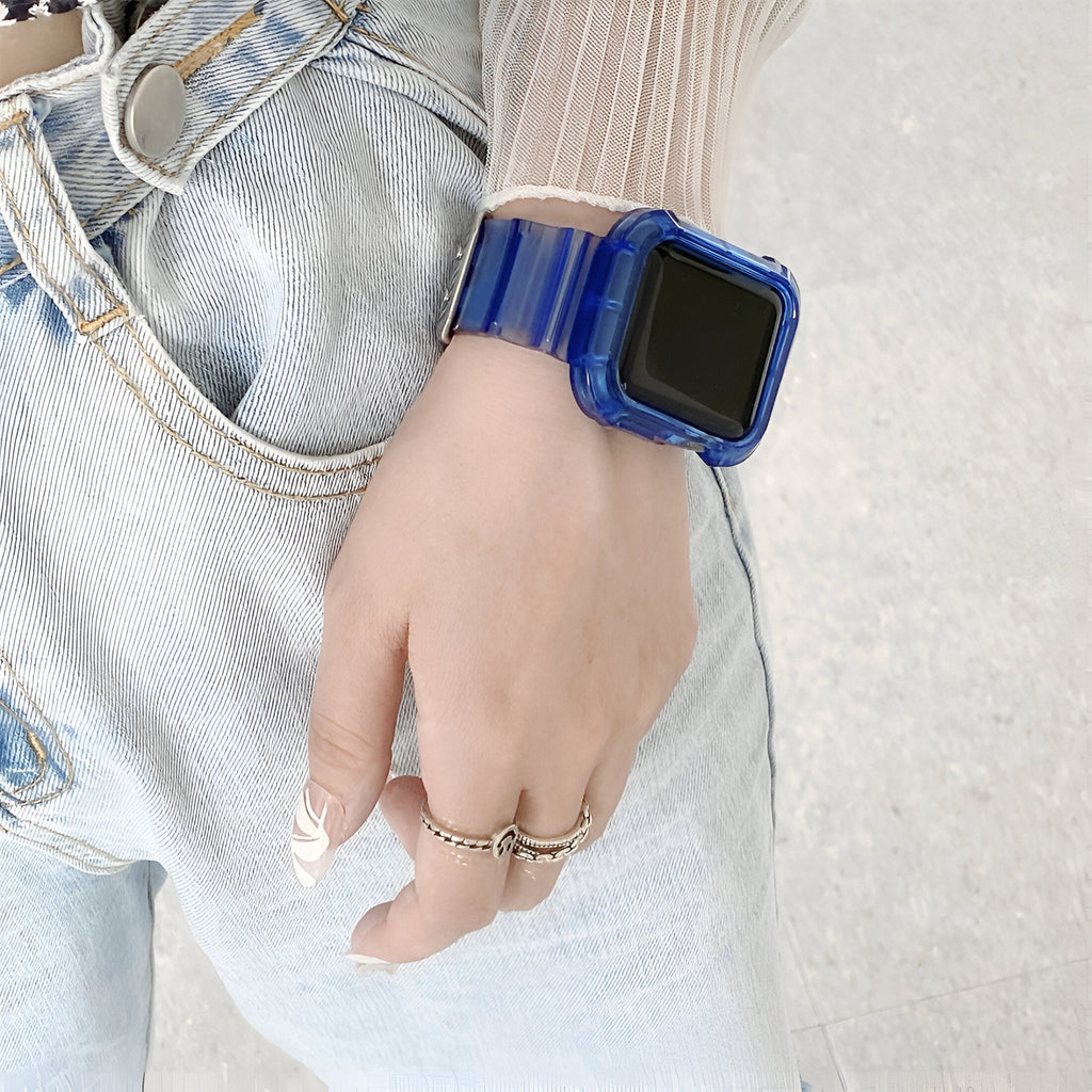 Bracelet Apple Watch en silicone bleu transparent porté sur poignet féminin avec jean clair et bagues fines argentées.