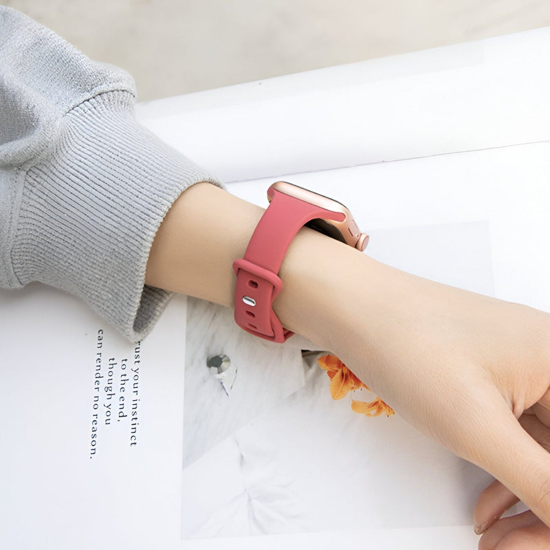 Bracelet Apple Watch silicone rose pour femme porté au poignet, style épuré et ajustable.