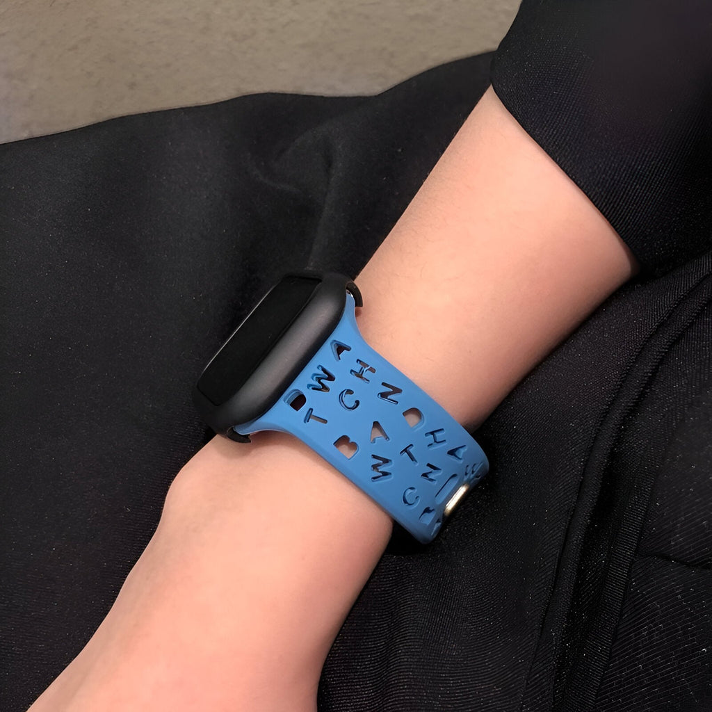 Bracelet Apple Watch en silicone bleu clair avec motifs lettres noires sur poignet féminin.