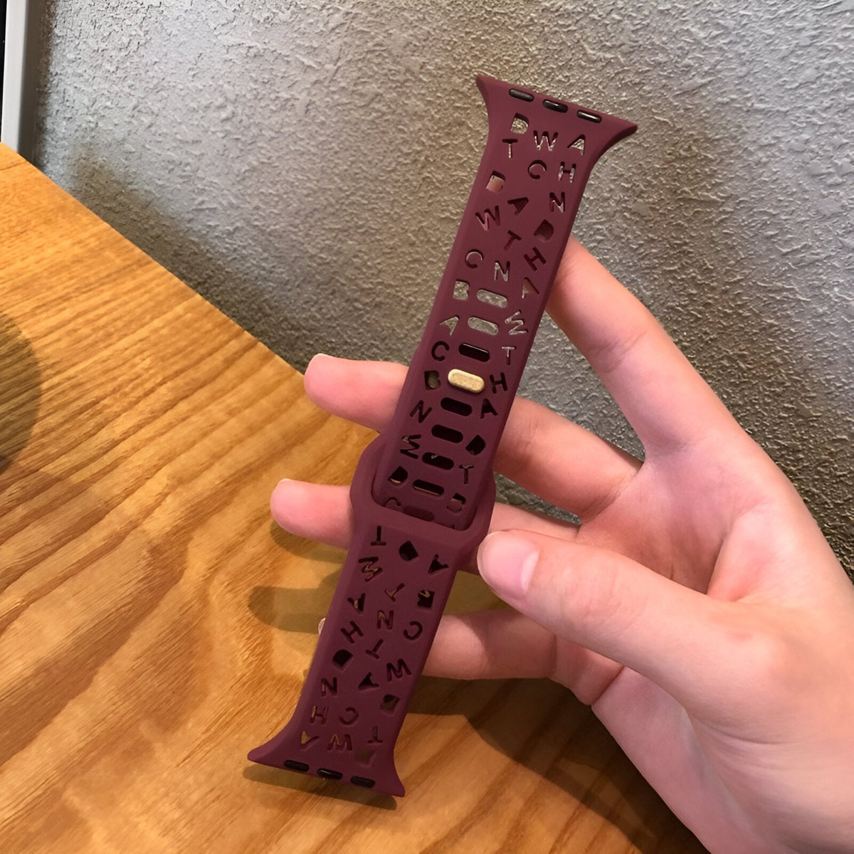 Bracelet Apple Watch en silicone bordeaux perforé avec motifs découpés et passant réglable.