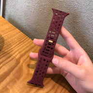 Bracelet Apple Watch en silicone bordeaux perforé avec motifs découpés et passant réglable.