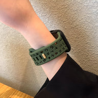 Bracelet Apple Watch vert en silicone avec motifs alphabétiques découpés sur poignet féminin.