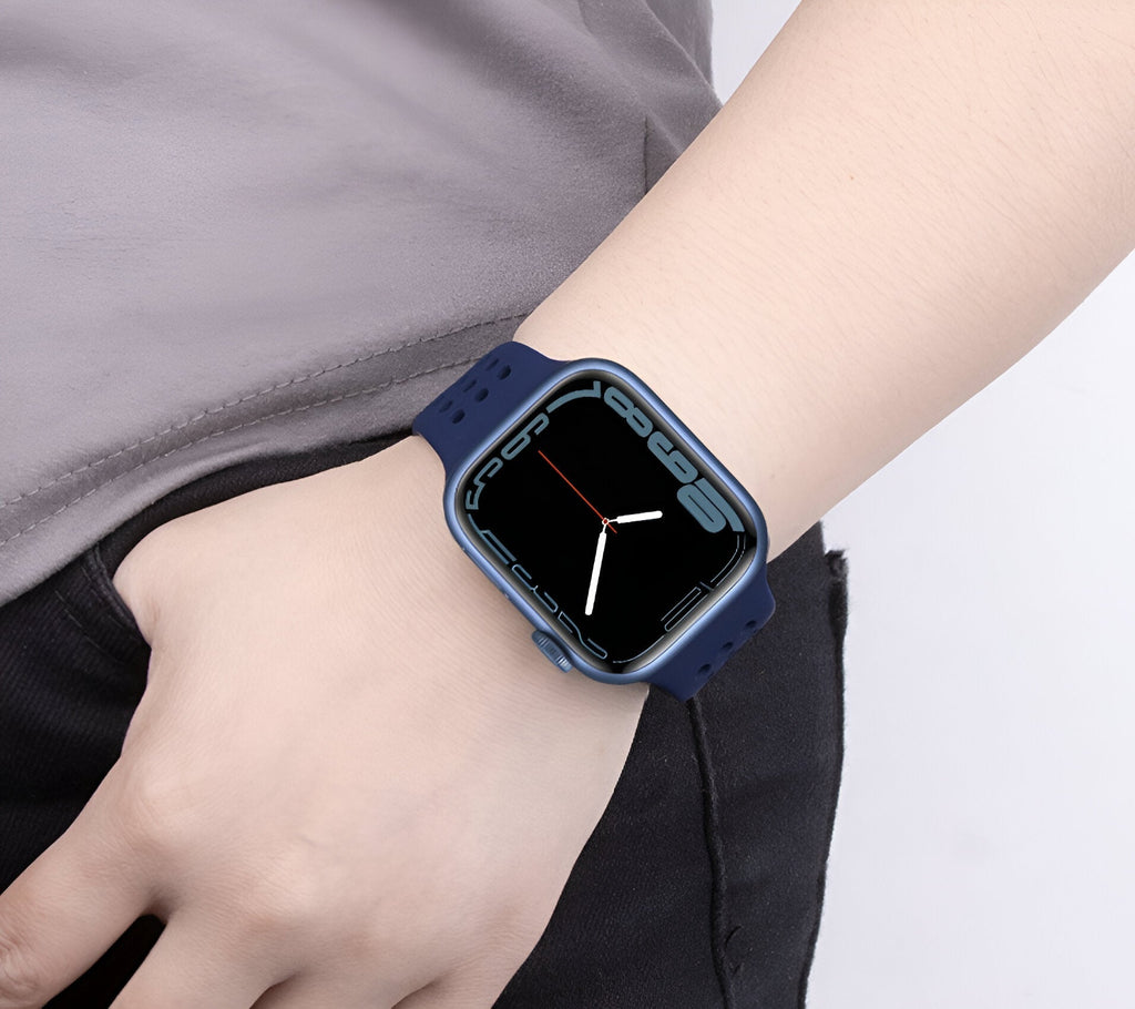 Bracelet Apple Watch en silicone bleu marine, ajustable, porté au poignet féminin.