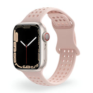 Bracelet Apple Watch en silicone rose pâle perforé pour femme, style sport et ajustable.