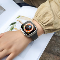 Bracelet Apple Watch Zora en silicone noir, porté au poignet féminin, avec cadran coloré numérique.