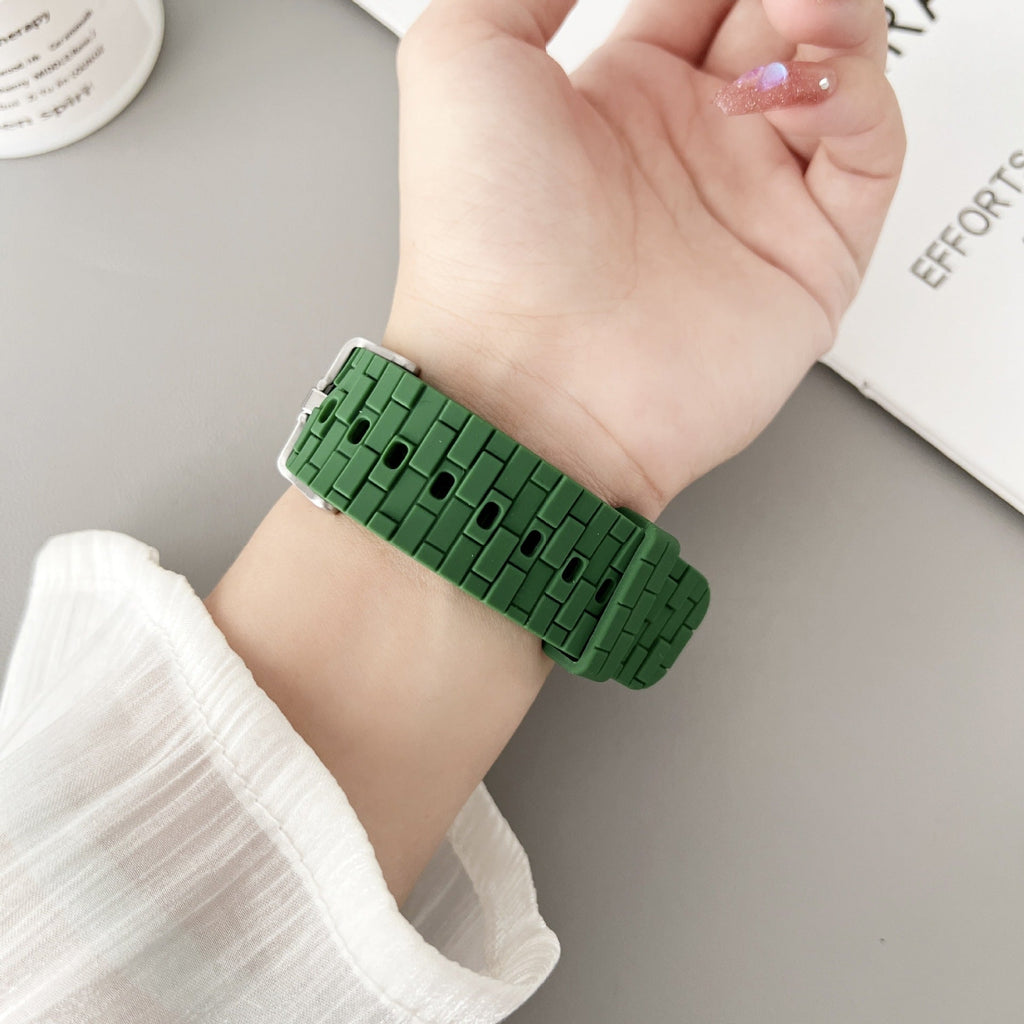 Bracelet Apple Watch en silicone vert style brique, fermé autour du poignet féminin.