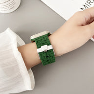 Bracelet Apple Watch en silicone vert style brique avec boucle argentée porté au poignet féminin.