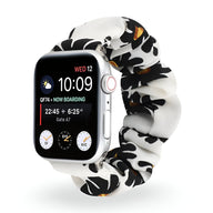 Bracelet Apple Watch en tissu élastique blanc à motif floral noir et orange, style scrunchie.