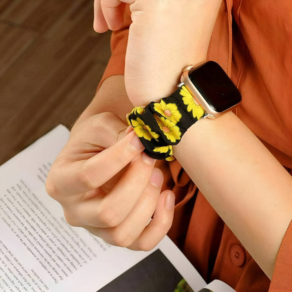 Bracelet Apple Watch en tissu élastique noir avec motifs floraux jaunes lumineux.