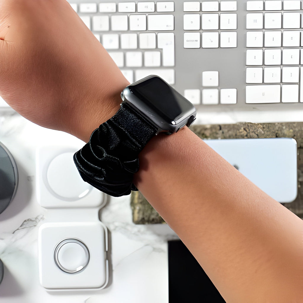 Bracelet Apple Watch noir en tissu élastique style scrunchie pour femme, ajusté au poignet.