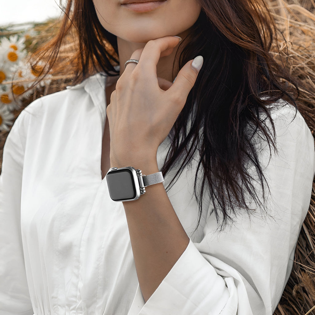 Bracelet Apple Watch maille milanaise or rosé, porté sur poignet femme avec chemise blanche.