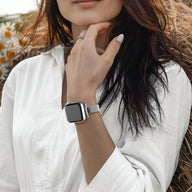 Bracelet Apple Watch maille milanaise or rosé, porté sur poignet femme avec chemise blanche.