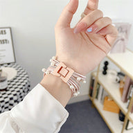 Bracelet multi-rangs à perles rose poudré avec fermoir carré pour Apple Watch, porté au poignet féminin.