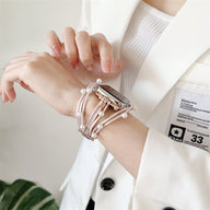 Bracelet multi-rangs à perles roses pour Apple Watch avec fermoir doré porté au poignet féminin.