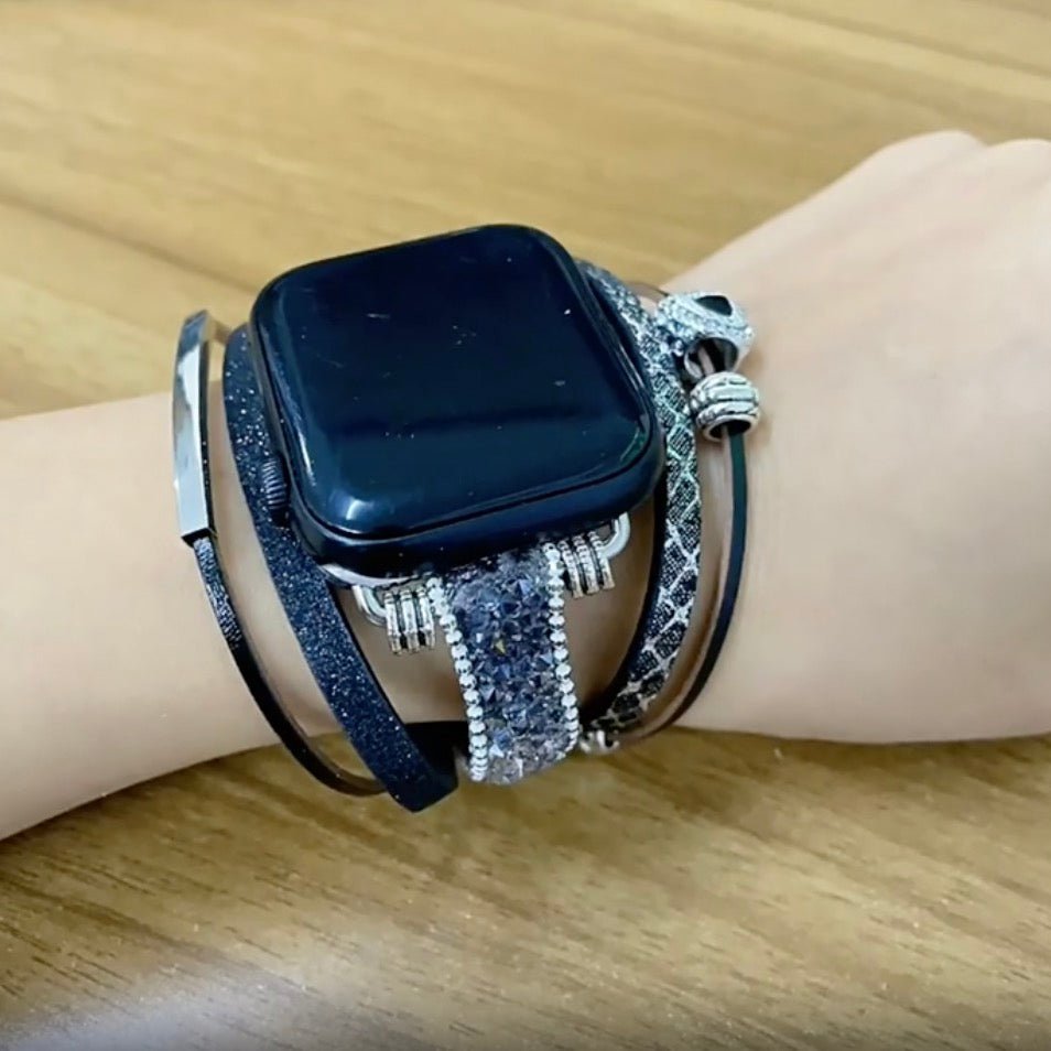 Bracelet Apple Watch multi-rangs noir avec charm cœur argenté porté au poignet féminin.