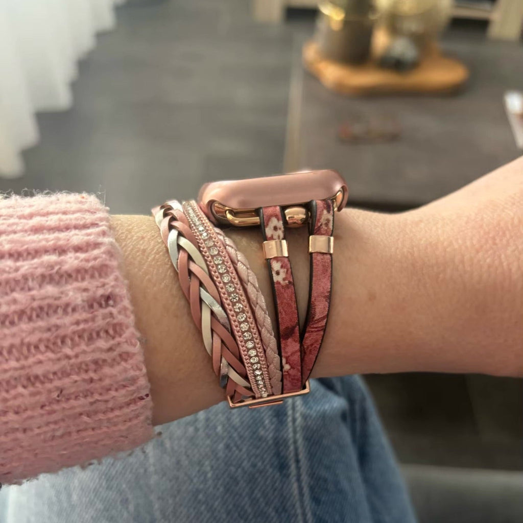Bracelet Apple Watch multi-rangs rose avec motifs floraux et détails en métal doré.