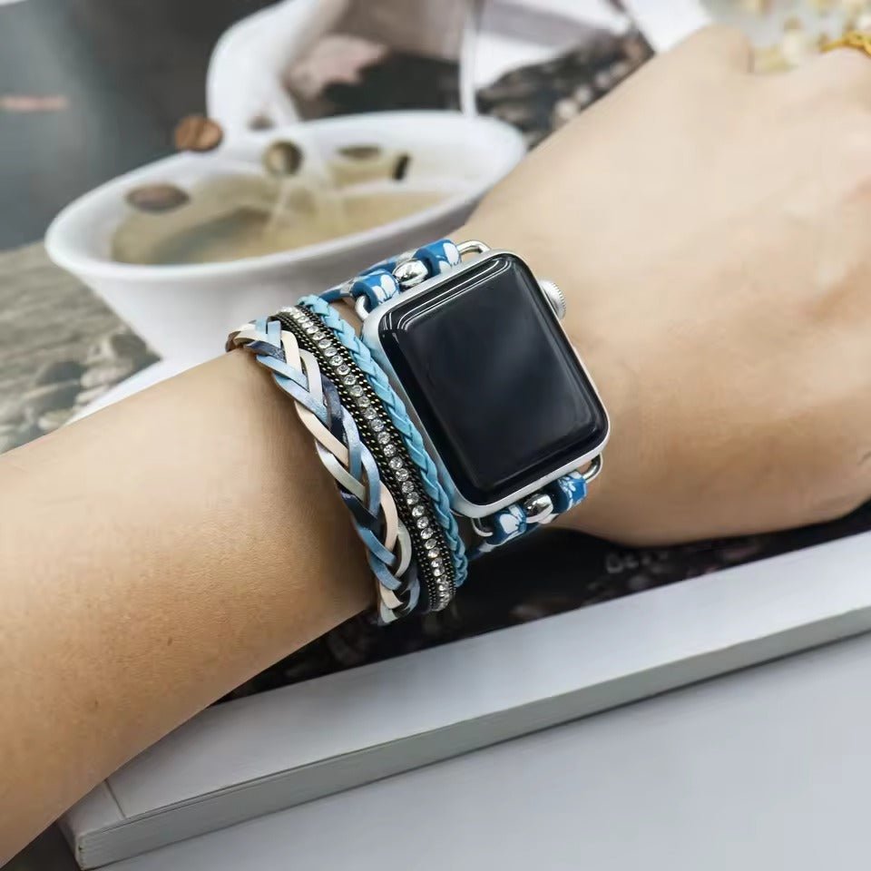 Bracelet multi-rangs bleu avec motif floral autour d'une Apple Watch noire sur poignet féminin.