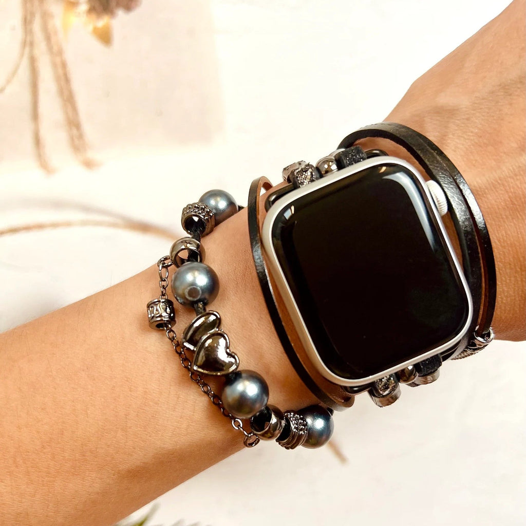 Bracelet Apple Watch noir multi-rangs avec charms variés et perles grises élégantes.