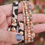 Bracelet Apple Watch multi-rangs perlé léopard noir et beige avec boutons dorés, style Malia pour femme.