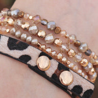 Bracelet Apple Watch multi-rangs perlé avec détails dorés et bande léopard en cuir doux.