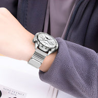 Bracelet de montre connectée argent en acier inoxydable à mailles fines sur poignet féminin.