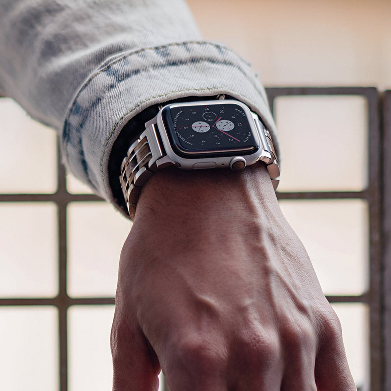 Bracelet pour Apple Watch en bois Zébrano avec maillons métalliques argentés sur poignet masculin.
