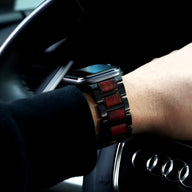 Bracelet de montre en bois de santal rouge et maillons noirs, compatible Apple Watch, porté au poignet homme.
