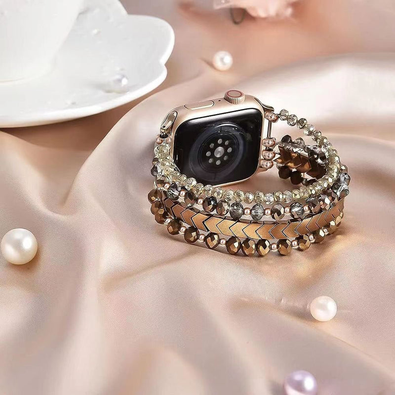 Bracelet en cristal scintillant couleur marron pour Apple Watch posé sur tissu satin rose pâle avec perles décoratives.